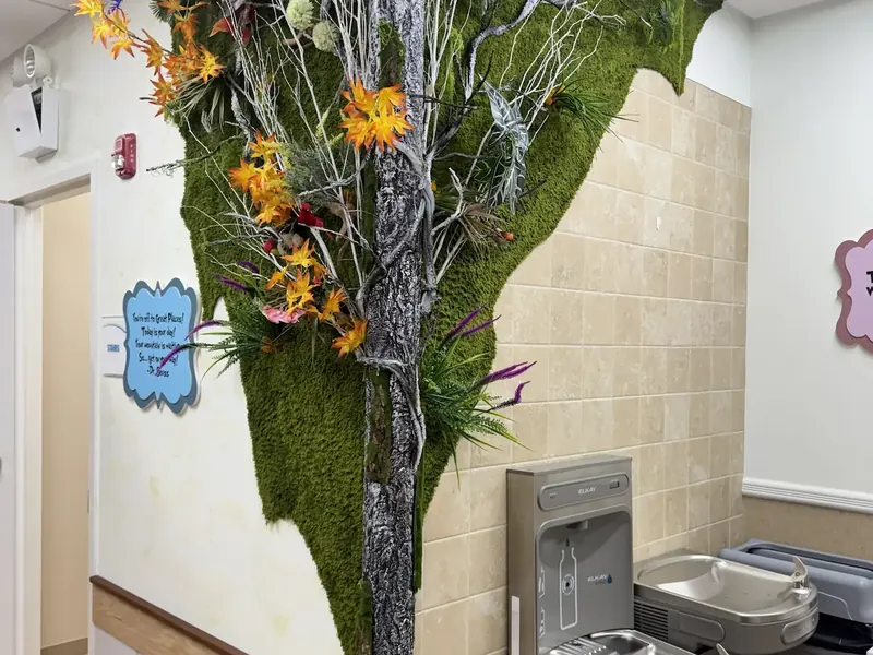 Preserved moss and foliage feature installed around a tiled column above a drinking fountain