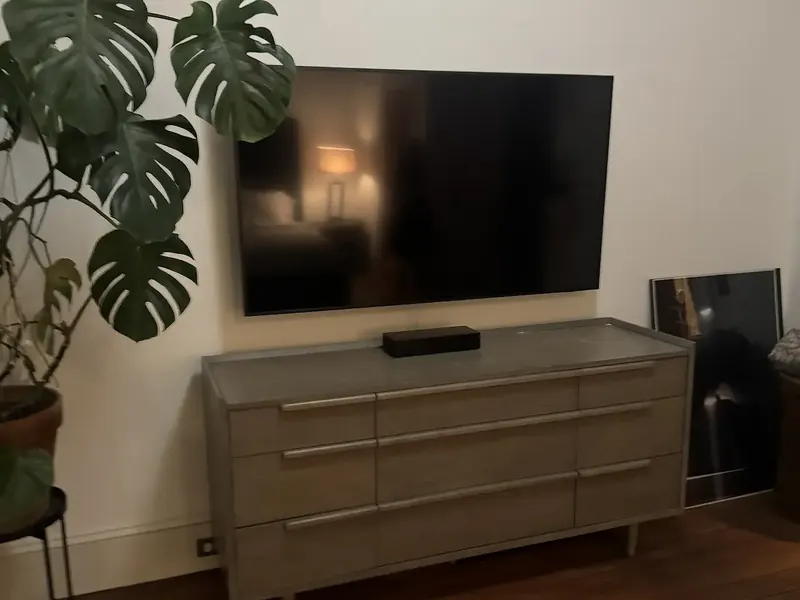 Television wall-mounted above a wooden dresser with the cables dropped out of sight
