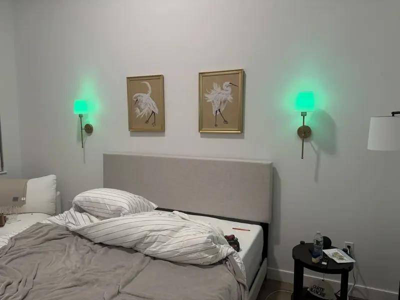 Pair of framed prints hung symmetrically between two wall sconces above a bed
