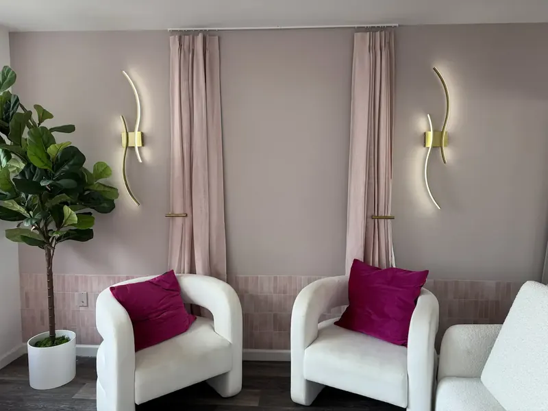 Sitting area with pale mauve walls, wall sconces and curtains in a matching tone