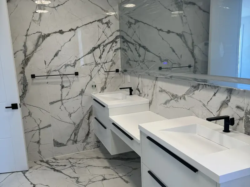 Marble-look tile behind a double vanity with the veining sequenced to continue across the joints